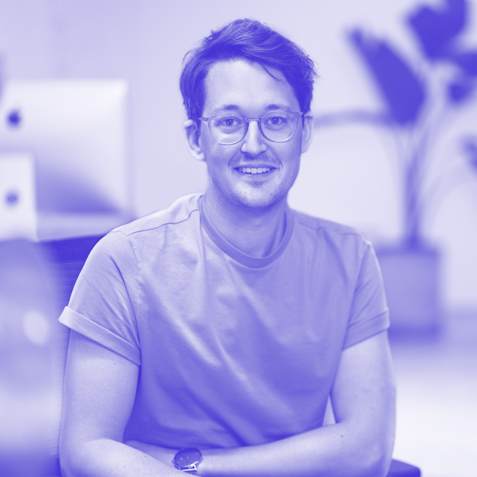 Mein Profilbild: Ich lächle freundlich vor einem modernen Büro-Hintergrund und präsentiere mich als kompetenter und kreativer Webdesigner und Webentwickler.